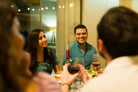 Happy cheerful woman and man talking having fun while eating dinner with a group of friends for a fun celebrationの写真素材