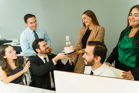 Group of businesspeople celebrating a birthday with some cake in the office