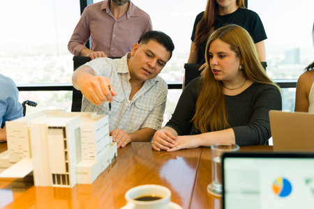 Male architect dressed casual explaining some building features to a client with a physical model