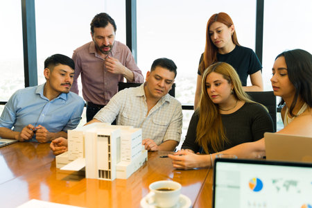 Group of architects in casual clothing looking at a building modelの写真素材