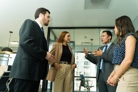 Four businesspeople having a discussion while standing in the office hallway