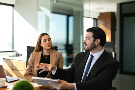Portrait of a Caucasian businessman in a suit sharing his ideas with a female client in a meeting roomの写真素材