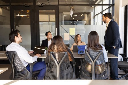 Group of businesspeople listening to a businessman while he makes a business presentation in a...