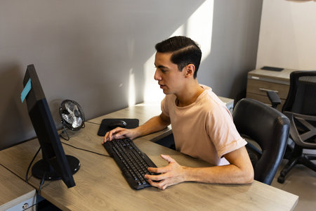 Good looking male worker sending some emails and checking on social media in an office computer