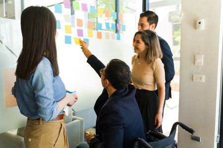 Rear view of a group of businesspeople working as a team and using sticky notes