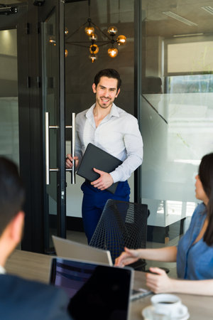 Good looking Caucasian businessman opening the door to a meeting room and asking permission to come...