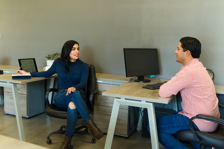 Beautiful Latin woman working in an office and having a chat with one of her coworkers