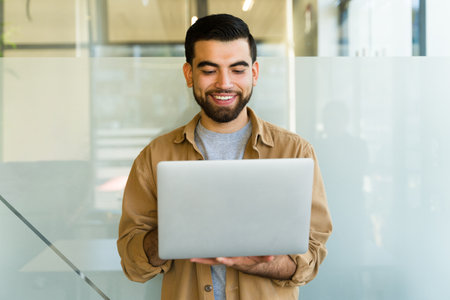 Portrait of a Latin office worker usign a laptop compuer while standingの写真素材