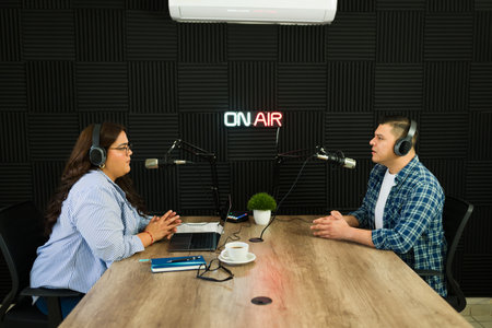 Young woman with her podcast guest in the recording studio for a talk show or podcast episode