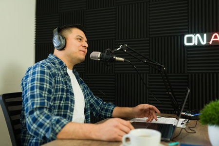 Attractive happy broadcast man enjoying talking during his podcast recording or radio show