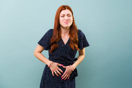 Redhead worried woman suffering from bad period cramps and in pain because of a stomachache virus