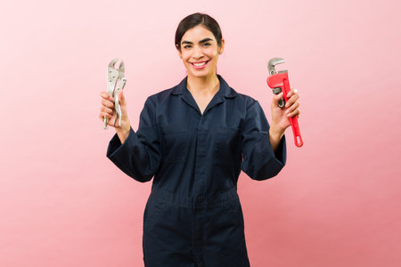 Cheerful attractive female plumber showing her tools and ready to work on repair looking happy...