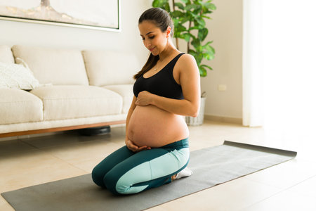 Active fit woman and expectant mother smiling touching her belly enjoying her pregnancy while...
