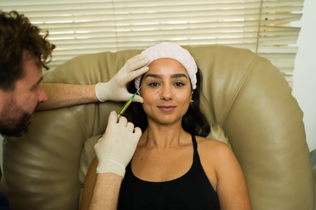 Beautiful happy woman at the alternative health clinic getting plasma PRP injections in her face while smiling with her doctorの写真素材