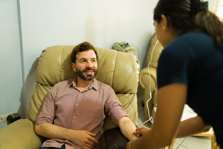 Attractive happy man talking to the nurse while getting alternative medicine and IV drip therapy for a myers vitamins cocktailの写真素材