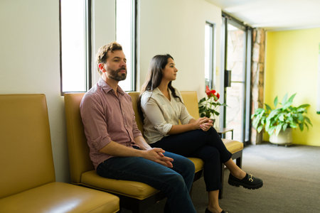 Latin couple sitting together in the waiting room of the health wellness clinic and waiting for the doctor or therapistの写真素材