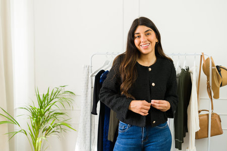 Happy Latin woman with a bright smile trying on a stylish jacket in a boutiqueの写真素材