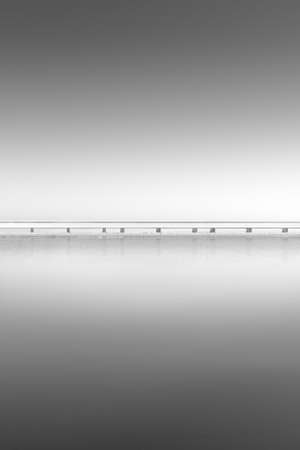 Division between a lake and the sky, through a bridgeの写真素材