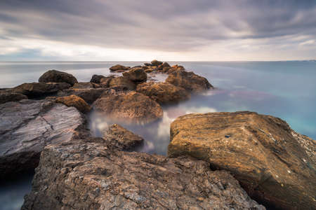 Long exposure shot in a rock breakwater located on the beach of El Palmera, in Almer?a (Spain)の写真素材