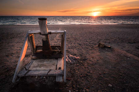 The sun falls behind an old wooden beached lathe, used to beach small boats, in the municipality of Las Salinas (Cabo de Gata), one of the most visited places in the province of Almeria in Spain.の写真素材