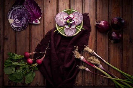 Variety of purple or purple vegetables, purple onions, radishes, red cabbage and tender garlic on the tableの写真素材