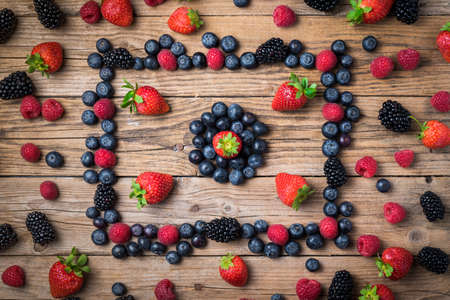 Fruits of the forest laid on a rustic wooden table, strawberries, blueberries, blackberries and...