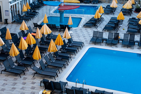 Swimming pool with yellow umbrellas in a summer day.のeditorial素材
