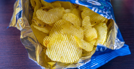 Crispy potato chips in plastic pack on wooden table background.の写真素材