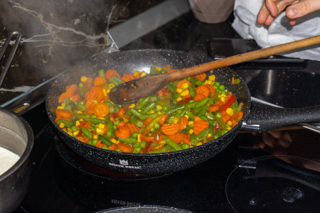 cooking vegetables in a wok on the fire stove in the kitchenの写真素材