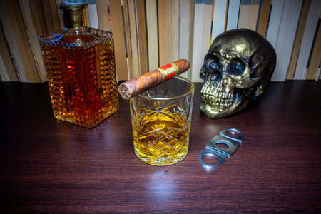 Skull, cigar and a glass of whiskey on a wooden tableの写真素材
