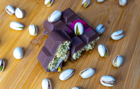 Chocolate bar with green kadayif and pistachio spread with pistachio nuts close upの写真素材