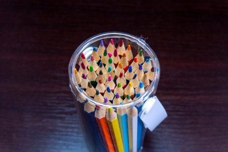 Colorful pencils in a glass jar on wooden table background.の写真素材