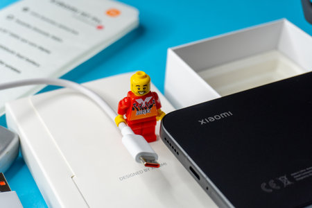 Arad,Arad Romania - November 18 2025: A black smartphone Lego man with a USB-C cable about to be plugged into its charging port on a white backgroundのeditorial素材