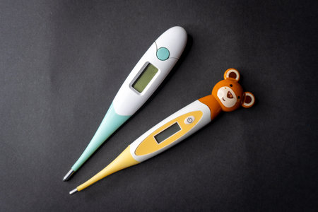 Electronic thermometer and teddy bear on black background, top viewの写真素材