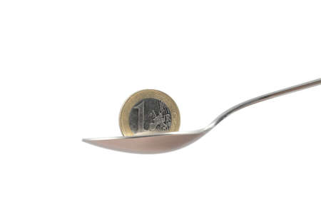 Euro coin over a stainless steel spoon with white isolated backgroundの写真素材