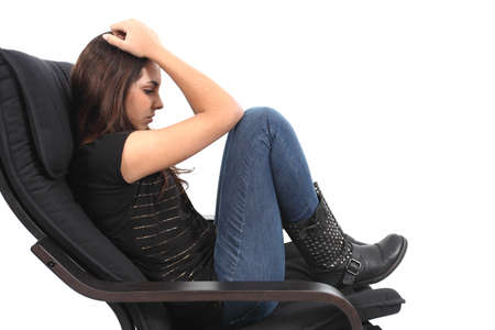 Beautiful girl worried seated on a coach with a white isolated background               の写真素材