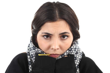 Very wrapped up ill girl with a thermometer on a white isolated backgroundの写真素材