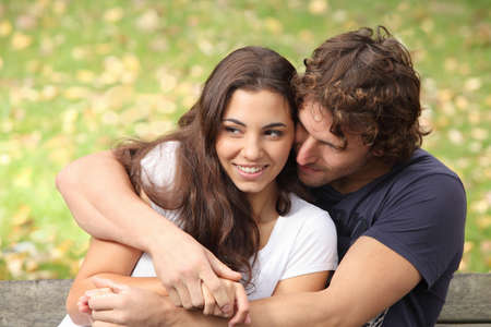Couple hugging in a park seated in a bench       の写真素材