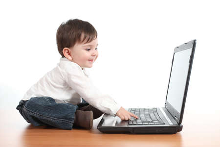 Casual baby smiling while is playing with a laptop computer in a white isolated backgroundの写真素材