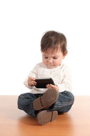 Casual baby concentrated in a mobile phone with a white isolated background の写真素材