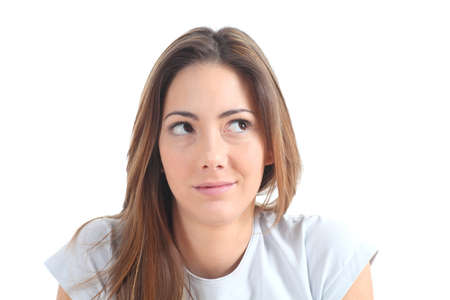 Woman thinking with her eyes looking at side on a white isolated backgroundの写真素材