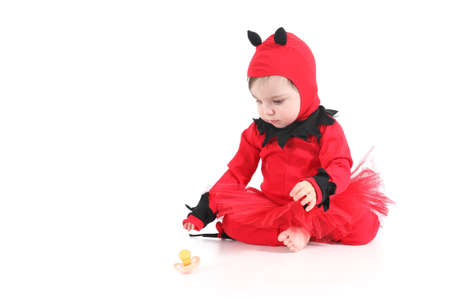 Baby with a red demon disguise watching a pacifier on a white isolated background        