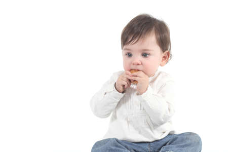 Baby absorbed eating a cookie on a white isolated background               の写真素材