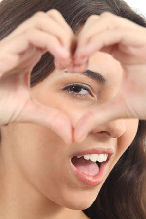 Beautiful woman making a heart shape with her hands on a white isolated backgroundの写真素材