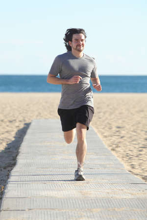 Front view of a man running on the beach with the sea in the backgroundの写真素材