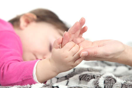 Baby sleeping takes the hand of her mother over a blanket in a white backgroundの写真素材