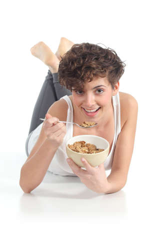 Beautiful woman eating corn flakes lying on a white isolated background               の写真素材