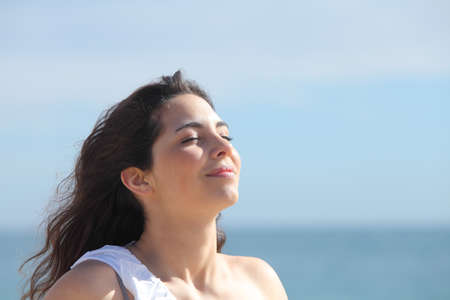 Beautiful girl breathing on the beach with the sea in the backgroundの写真素材