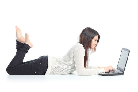 Beautiful woman lying and typing in a laptop on a white isolated background              の写真素材