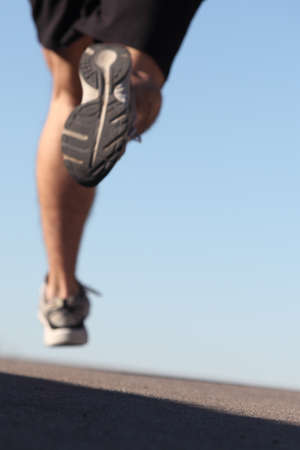 Unfocused man legs running on the asphalt with the sky in the backgroundの写真素材